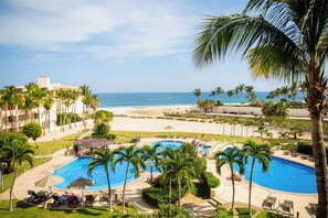 Ein Resort mit Swimmingpool, Palmen und Blick auf den Strand.