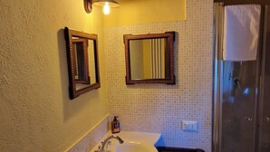 A bathroom with a white sink, a mirror, and a shower area.