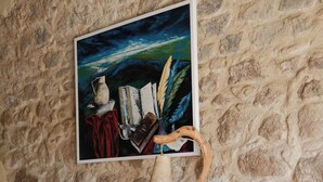 Un mur en pierre orné d’un tableau encadré, un bureau avec une lampe et un tapis à motifs.