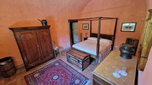 Una camera da letto tradizionale con un letto a baldacchino, un armadio in legno e un tavolino con una teiera.