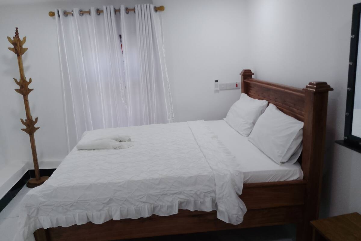 A neatly made bed with white linens, a wooden headboard, and a bedside table.