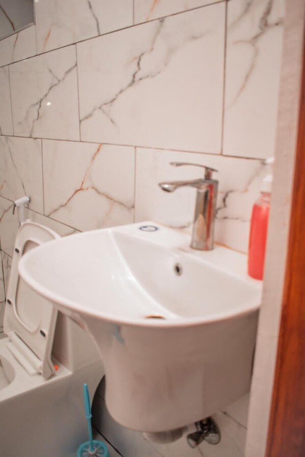 A bathroom with a white sink, a mirror, and a toilet.