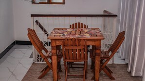 Une table à manger avec quatre chaises en bois, une nappe à motifs et une rambarde blanche derrière.