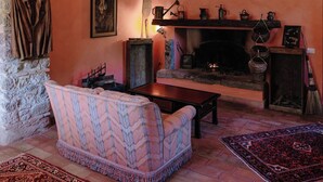 Ein gemütliches Wohnzimmer mit einem Steinbogen, einem Kamin, einer Couch und einem gemusterten Teppich.