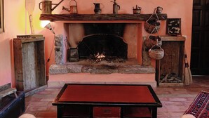 Ein gemütliches Wohnzimmer mit Kamin, einem Holztisch und einer Couch.