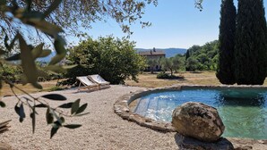 A pool with a pebble border, two lounge chairs, and a large rock in the foreground. - La Quinta - Suite with  living room and outdoor garden (Tolfa)