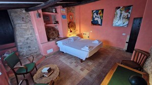 A cozy room with a bed, a small table, chairs, and artwork on the walls. - La Quinta - Suite with  living room and outdoor garden (Tolfa)