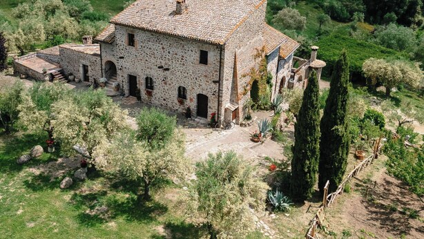 A stone building with a tiled roof surrounded by lush greenery and hills in the background. - La Quinta - Suite with  living room and outdoor garden (Tolfa)