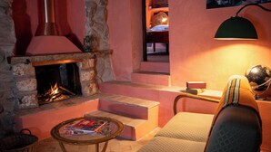 A cozy room with a stone fireplace, a comfortable armchair, a small table with magazines, and a lamp. - La Quinta - Suite with  living room and outdoor garden (Tolfa)