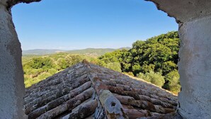 A view through a stone archway overlooking a terraced roof and lush green landscape. - The Poet - Classic Room - Panoramic Attic Room (Tolfa)