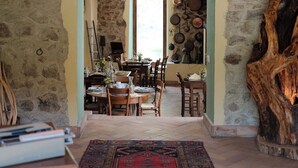 A rustic interior with stone walls, a wooden dining area, and a large rug. - The Poet - Classic Room - Panoramic Attic Room (Tolfa)
