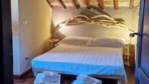 A bedroom with a wooden ceiling, a bed with white bedding, and a nightstand with a lamp. - The Poet - Classic Room - Panoramic Attic Room (Tolfa)