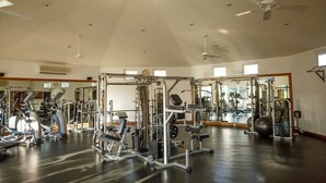 A spacious gym with various exercise machines, a large mirror, and a high ceiling with a skylight. - Las Mañanitas LM E3303 (San José del Cabo)