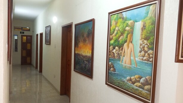 Un corridoio con opere d'arte incorniciate alle pareti, una porta in fondo e un pavimento piastrellato.