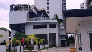 A modern hotel with a multi-story structure, a gated entrance, and a well-maintained lawn with palm trees. - W/ Secure Cabinets, complete appliance + Wifi (Davao City)