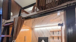 A compact room with a wooden wardrobe, a black office chair, a small wooden table, and a hanging curtain. - W/ Secure Cabinets, complete appliance + Wifi (Davao City)