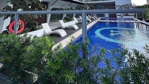 A modern hotel with a swimming pool, lounge chairs, and a tall building in the background. - W/ Secure Cabinets, complete appliance + Wifi (Davao City)