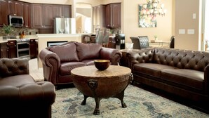 A living room with a brown leather sofa, a round coffee table, and a patterned rug. - -Arbor Grand Estate- (Leesburg)