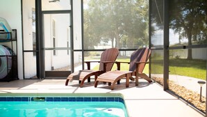 A poolside area with a glass-enclosed patio, two Adirondack chairs, and a view of a residential neighborhood. - -Arbor Grand Estate- (Leesburg)