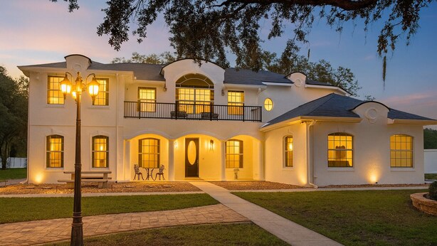 A two-story house with a balcony, multiple windows, and a well-lit entrance. - -Arbor Grand Estate- (Leesburg)