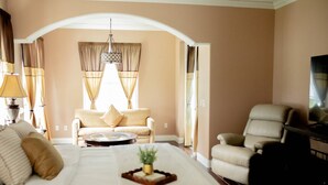 A hotel room with a large bed, two armchairs, a sofa, a TV, and a chandelier. - -Arbor Grand Estate- (Leesburg)