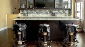 A kitchen with dark wooden cabinets, a granite countertop, and a built-in TV. There are three stools with leather seats. - -Arbor Grand Estate- (Leesburg)