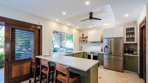 A modern kitchen with a central island, stainless steel appliances, and a ceiling fan.