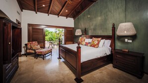 A spacious bedroom with a large bed, wooden furniture, and a view of greenery outside.