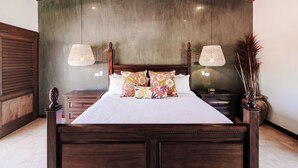 A wooden bed with a white bedspread and colorful floral pillows, flanked by two nightstands with lamps.