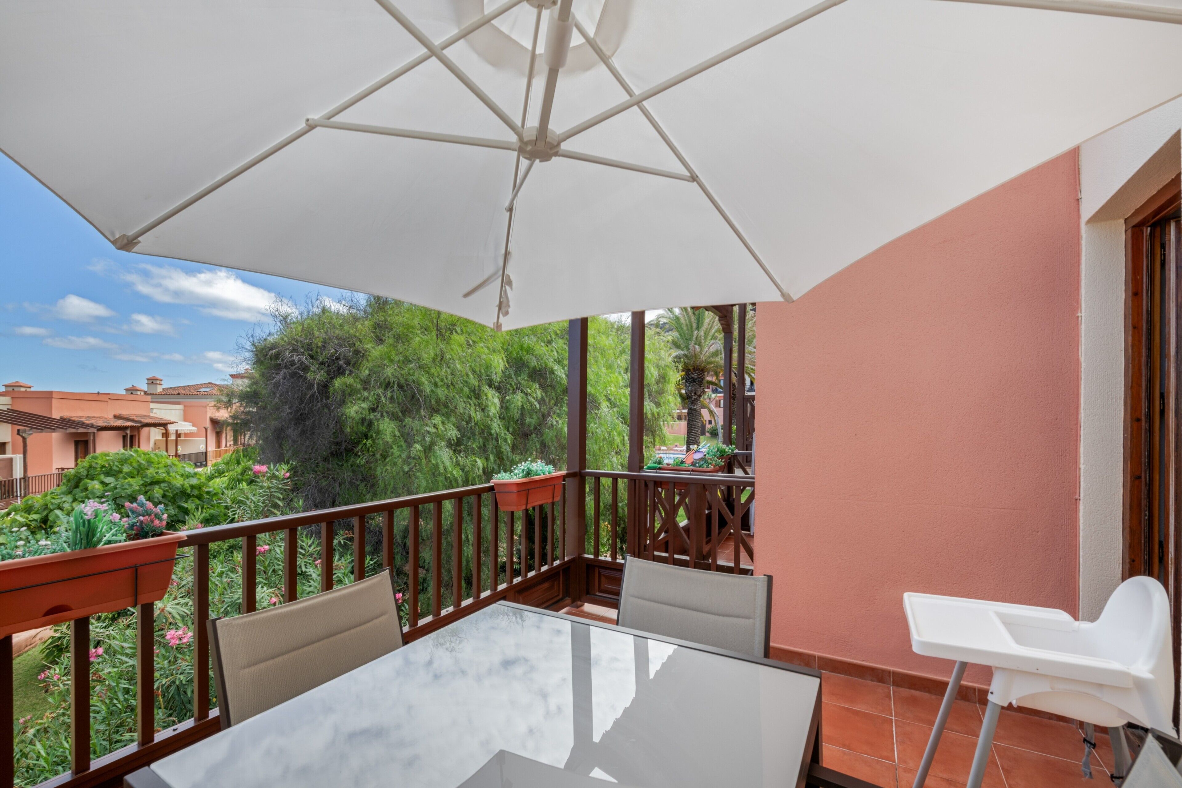 Ein Balkon mit Tisch, Stühlen und einem weißen Sonnenschirm.
