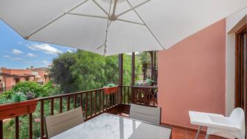 Ein Balkon mit Tisch, Stühlen und einem weißen Sonnenschirm.