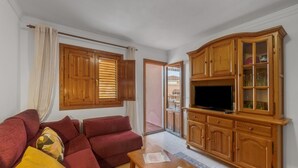 Ein Wohnzimmer mit einer Couch, Holzschränken und einem Fernseher.