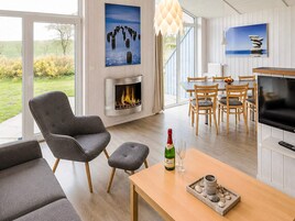 Ein modernes Wohnzimmer mit Kamin, Essbereich und Fernseher.