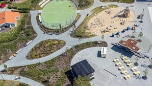 Vue aérienne d’un complexe sportif comprenant un terrain de basket-ball, une aire de jeux et un parking.