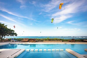 Área da piscina com espreguiçadeiras e vista para o oceano.