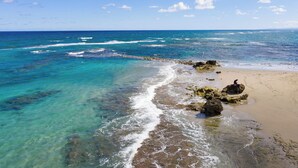 A beach with clear turquoise waters and rocky outcrops.