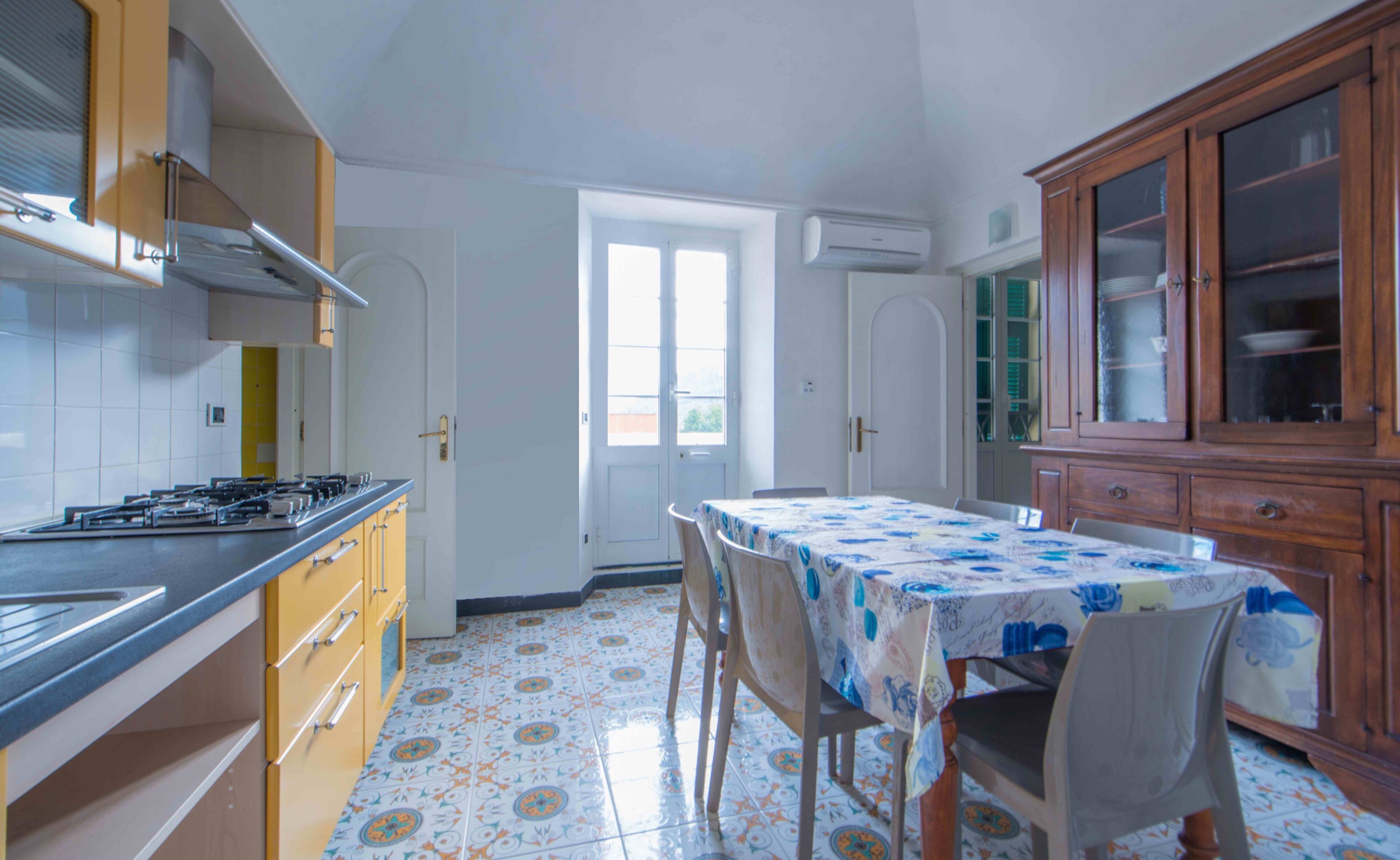 Une cuisine équipée d’une cuisinière à gaz, de meubles en bois et d’un sol carrelé.