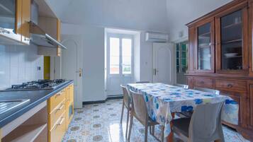 Une cuisine équipée d’une cuisinière à gaz, de meubles en bois et d’un sol carrelé.
