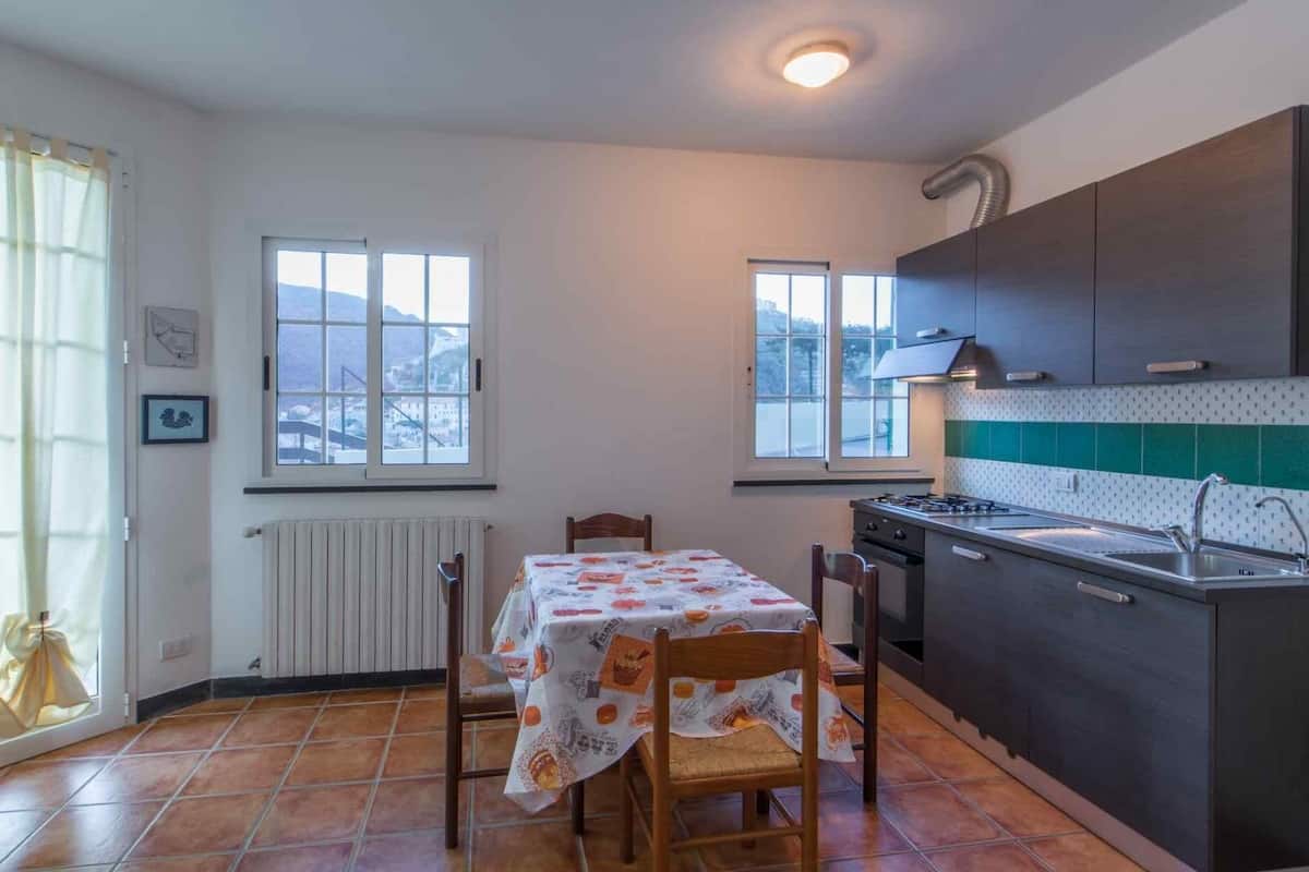 Eine Küche mit Esstisch, Stühlen, Herd und Fenster mit Außenblick.