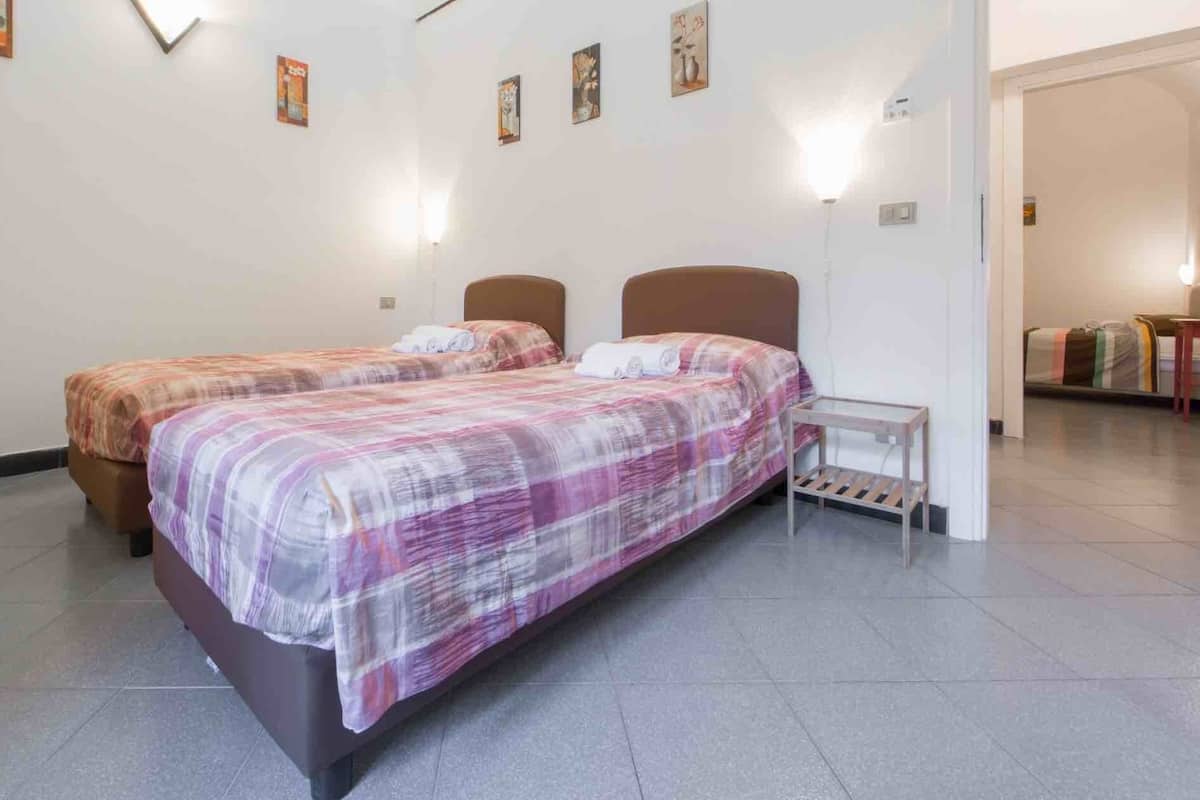 Ein Hotelzimmer mit zwei Betten, einem kleinen Tisch und einer Wand mit gerahmten Bildern.