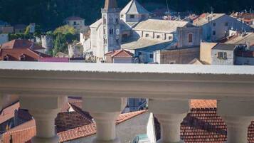 A balcony with a view of a town featuring historic buildings and a prominent church tower.
