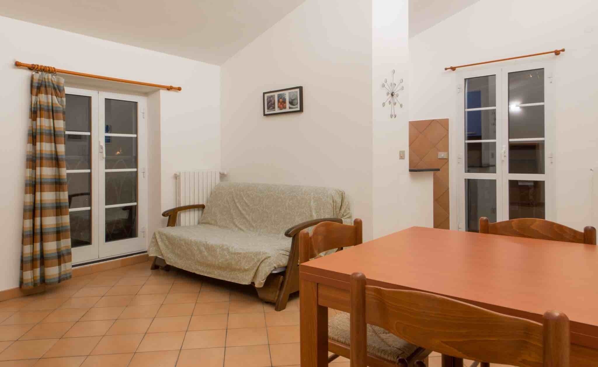 Una habitación con una mesa de comedor, un sofá, una ventana con cortinas y un radiador.