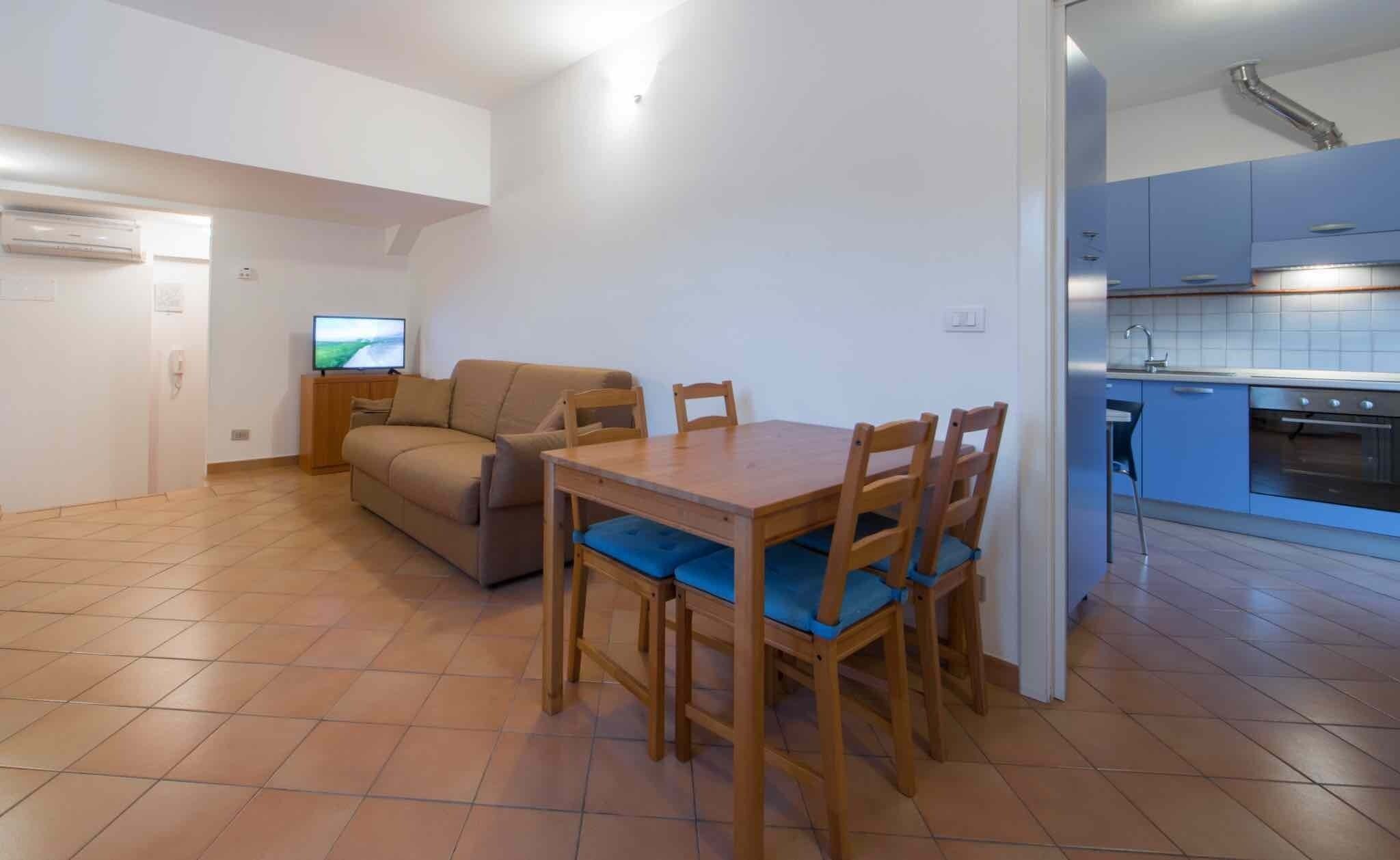 A compact living space with a dining area, kitchenette, and a sofa.