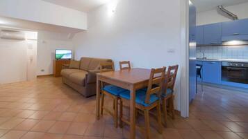 A compact living space with a dining area, kitchenette, and a sofa.