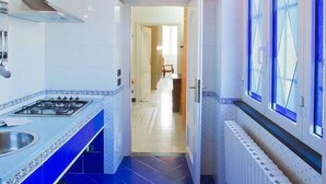 Una cocina con estufa a gas, armarios blancos y azulejos azules y blancos.