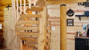 A wooden spiral staircase in a cabin-style interior with a wooden ceiling and walls, a coffee station, and a black cabinet. - Custom Log Home directly along the Greenbrier River sits the River Ridge Retreat (Marlinton)