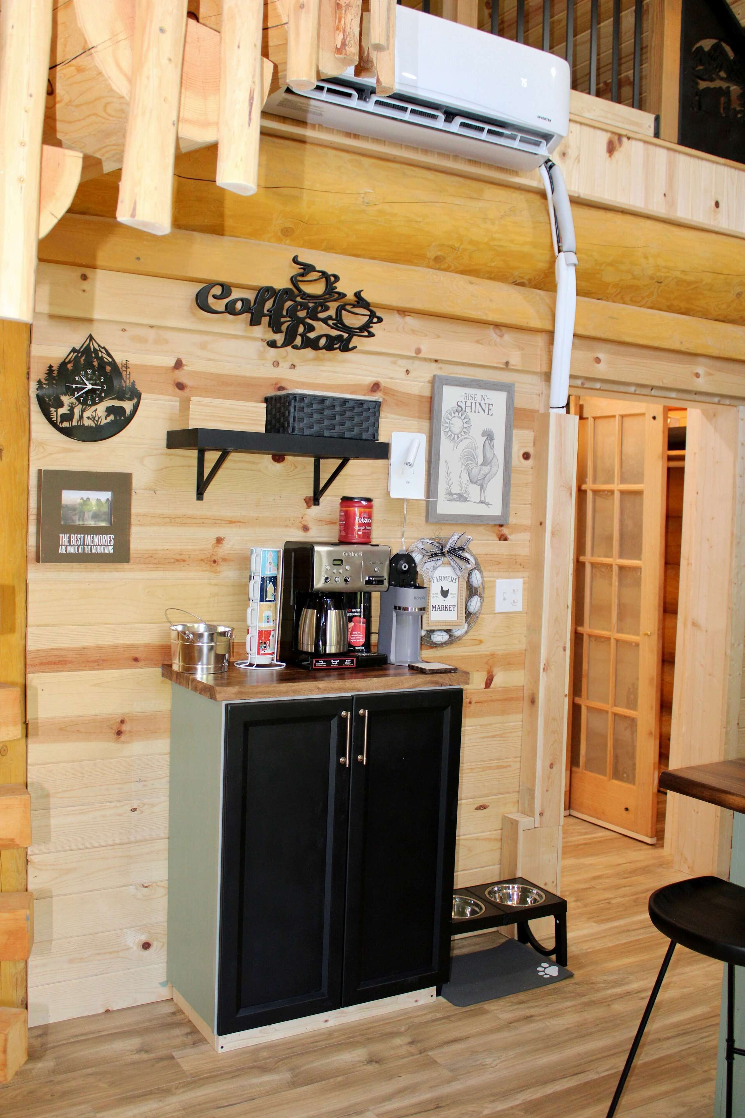 Een houten interieur met een koffiehoek, een ingelijst beeld en een voerbak voor een hond.