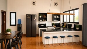 Una cocina moderna con una isla central, taburetes de bar, una mesa de comedor y un dispensador de agua.