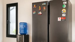 Un refrigerador negro con múltiples imanes y dispensador de agua.