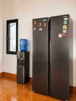 A black refrigerator with multiple magnets and a water dispenser.